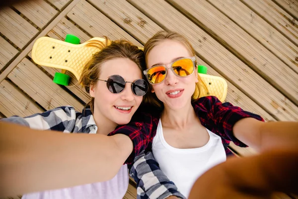 Due giovani ragazza in abito hipster fare selfie mentre sdraiato con sul molo di legno — Foto Stock