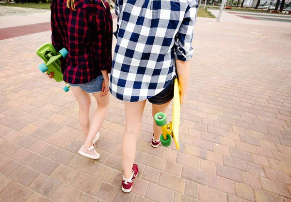Zwei urbane Mädchen mit Longboards in karierten Hemden auf der Straße in der Stadt — Stockfoto