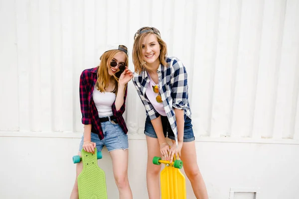 两个开朗有趣的女孩穿着格子衬衫, 在街上的墙壁上摆姿势 — 图库照片