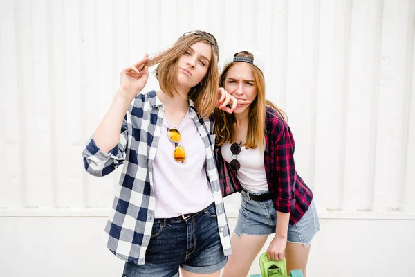 Deux joyeuses filles drôles portant des chemises à carreaux posant contre le mur de la rue dans la rue — Photo