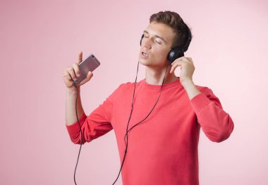 Bir akıllı telefon ile bir müzik dinlerken kulaklık ile genç yakışıklı bir adam portresi