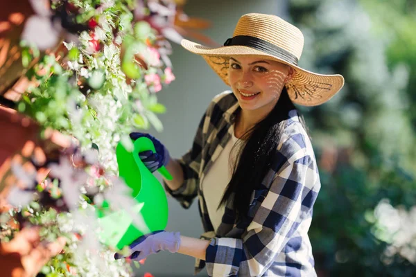 Hermosa mujer jardinero regando plantas en el jardín en el día caluroso de verano. Concepto de jardinería —  Fotos de Stock