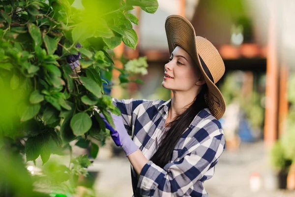 Mooie jonge vrouw in geruite shirt en stro hoed tuinieren buiten op een zomerdag — Stockfoto
