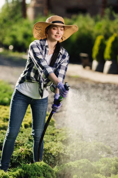 Linda jovem jardineiro mulher rega jardim no dia quente de verão — Fotografia de Stock