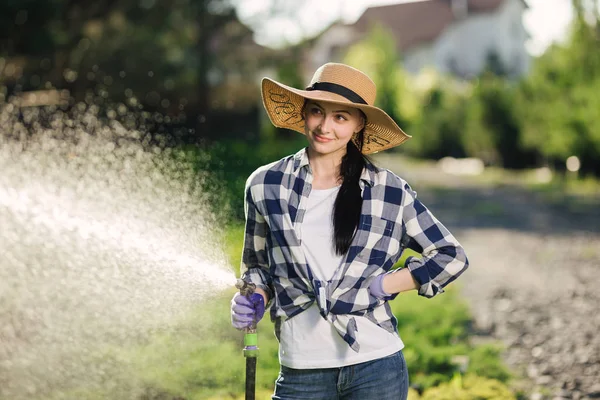 Krásný mladý zahradník žena zalévání zahrady v horkém letním dni — Stock fotografie