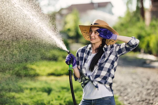 Hermosa joven jardinero mujer riego jardín en caluroso día de verano — Foto de Stock
