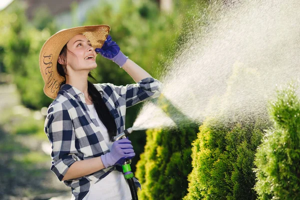 Hermosa joven jardinero mujer riego jardín en caluroso día de verano — Foto de Stock