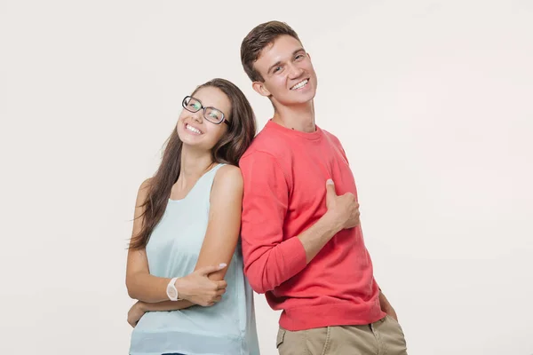 Feliz jovem lindo casal de pé de volta para trás e sorrindo olhando para a câmera no fundo branco — Fotografia de Stock