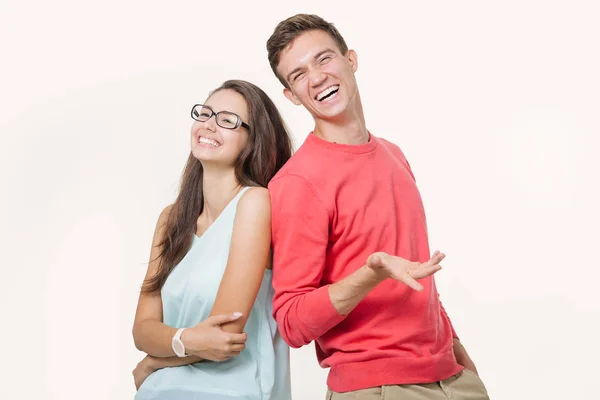 Happy young lovely couple standing back to back and smiling looking at camera on white background — Stock Photo, Image