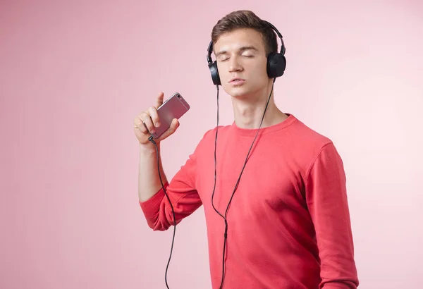 Porträtt av en ung stilig man med hörlurar en musik med en smartphone — Stockfoto