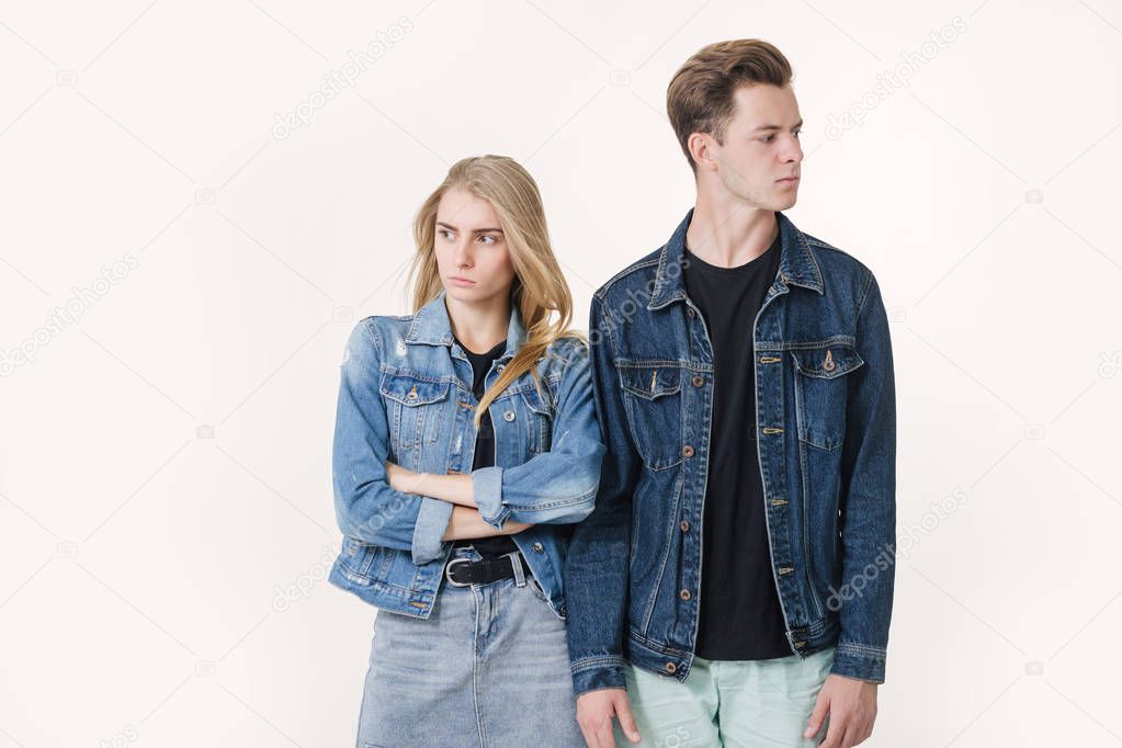 Studio shot of disgruntled couple wearing casual clothes standing back to back frowning their faces. Discord in the relationship. Divergence of points of view.