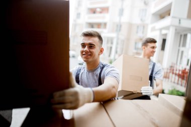 Genç bir üniforma yakışıklı gülümseyen hareket ettirmek için kutu kutu dolu minibüs boşaltma sırasında ulaşıyor. Ev taşımak, taşıyıcı Servisi