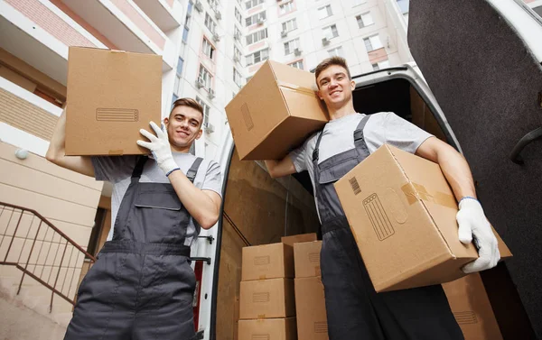 Two young movers are at their work near their car in a courtyard — Stock Photo, Image