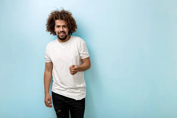 En curly-headed brunet står man med en hand som sträcks ut, ser intresserad med passion i ögonen. Kommunikativa och sällskaplig. — Stockfoto