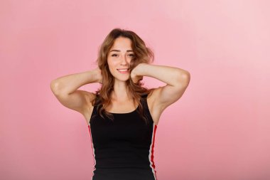 Pembe arka plan siyah elbise giyen genç neşeli sarışın kadın portresi