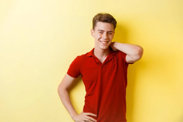 Přátelský, vesele Evropské chlap na sobě červené tričko s úsměvem stojící nad žlutým pozadím — Stock fotografie