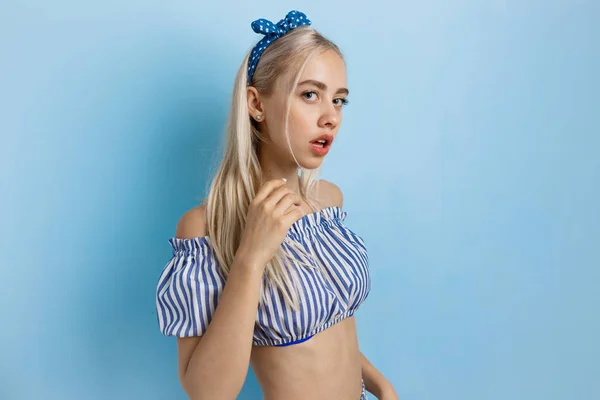 Nyugodt és érzéki gyönyörű szőke lány nyári ruhában, pózol a kamera, kék háttér áll — Stock Fotó