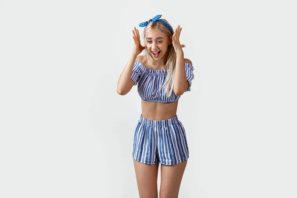 Joyful e super animado linda menina loira em roupa de verão, sorrindo e rindo de pé sobre fundo branco — Fotografia de Stock