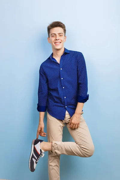 Handsome friendly looking cheerful european guy wearing blue shirt smiling standing over blue wall — Stock Photo, Image