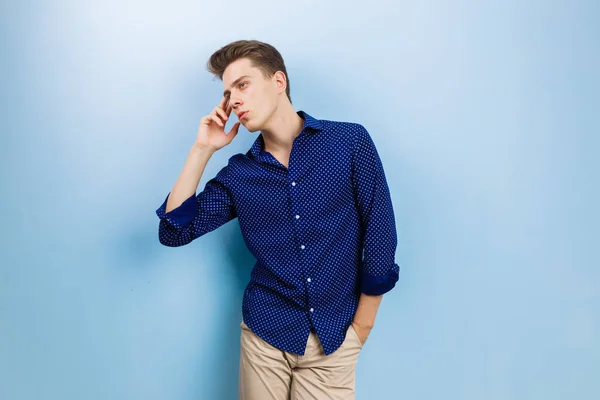 Calme réfléchi beau garçon brun portant chemise bleue et pantalon beige, debout contre le mur bleu — Photo