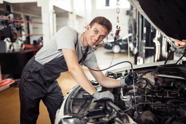 Yakışıklı bir mekanik bir motor denetlerken gülümsüyor