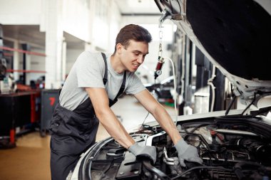 Bir adam onun iş yerinde bir araba motoru kontrol ediyor