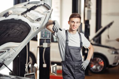 Genç tamirci o onarıyor bir arabanın yakınında duruyor