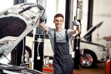 Genç bir automechanic bir araba servisinde car yakınındaki duruyor