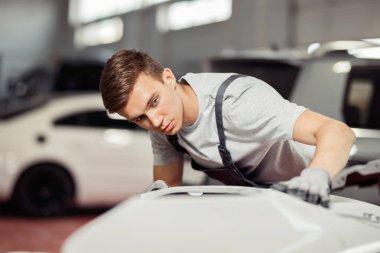 Genç tamirci beyaz spor araba düzeltmeye odaklanmıştır