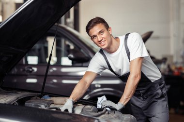 Gülümseyen bir automechanic bir araba tamir ediyor