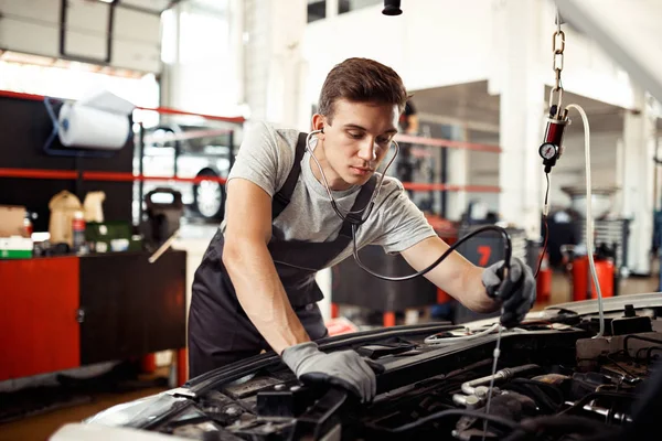 Ein junger Mann ist mit der Überprüfung eines Automotors beschäftigt: Autoreparatur und -wartung — Stockfoto