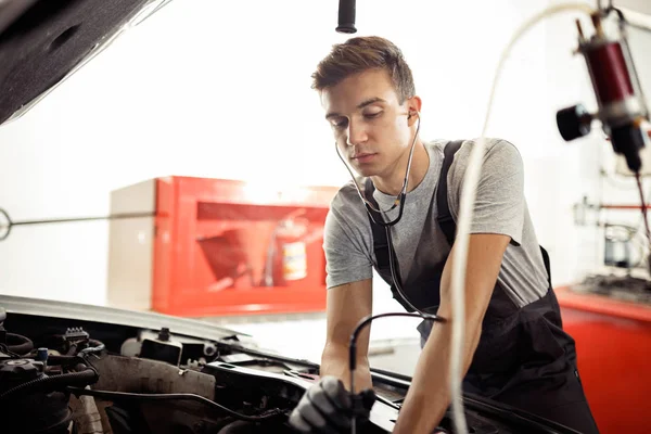 Un joven está revisando el motor de un auto. — Foto de Stock