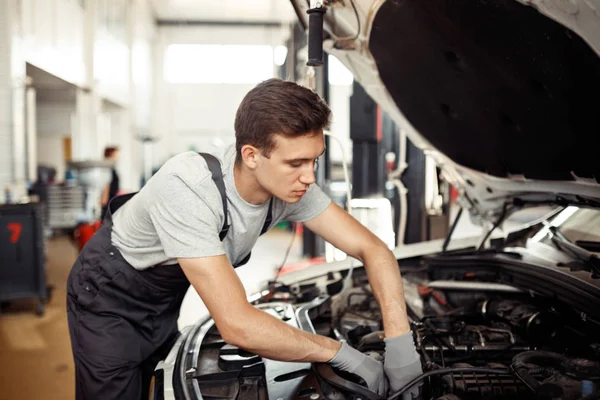 Ein gelernter Kfz-Mechaniker repariert ein Auto beim Autoservice — Stockfoto