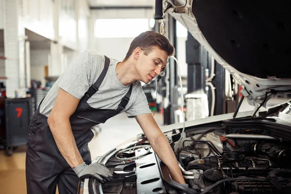 Ein Mechaniker repariert ein Auto bei einem Autoservice und bei der Fahrzeugwartung — Stockfoto