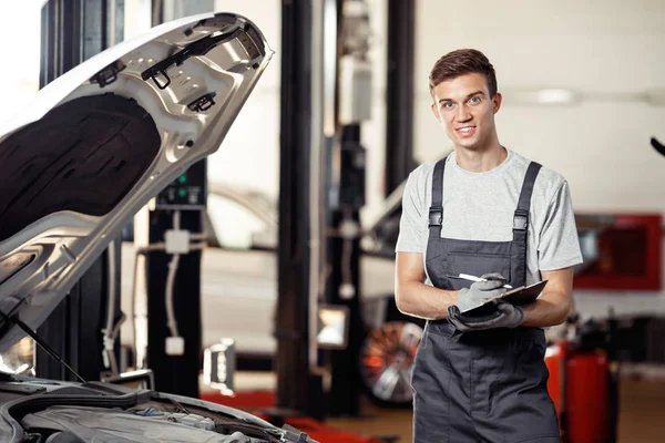 Un mecánico calificado está en su trabajo mientras revisa un automóvil — Foto de Stock