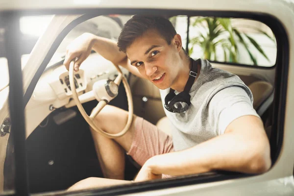 Um jovem está sentado em um carro antigo — Fotografia de Stock