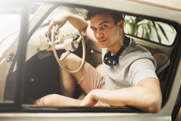Atrakcyjny mężczyzna młody siedzi w zabytkowych samochodów — Zdjęcie stockowe