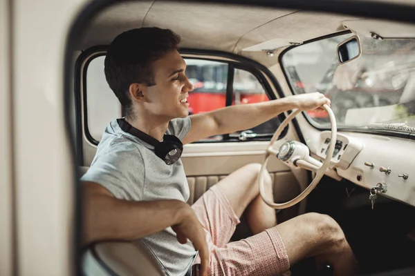 Un homme jeune et séduisant conduit une voiture vintage — Photo