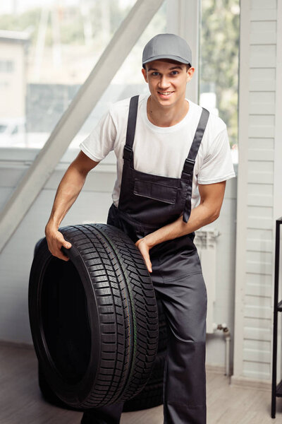 Молодой человек в форме несёт шину.
