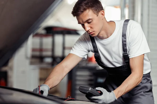 Concentrado en su trabajo mecánico es la reparación de un coche en un servicio de coches — Foto de Stock