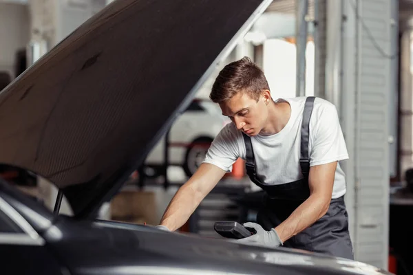 Un joven está reparando un motor de vehículo en el mantenimiento de un coche — Foto de Stock