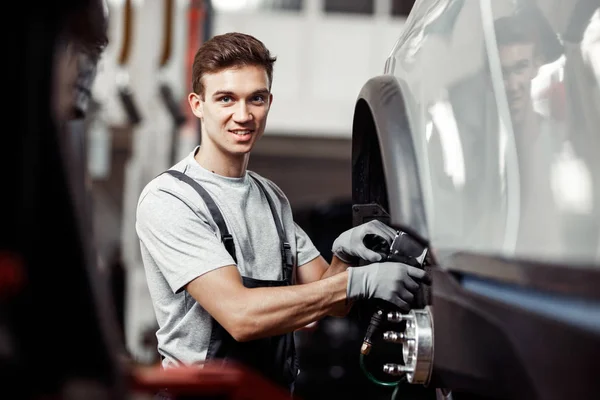 Un jeune mécanicien sourit alors qu'il travaille dans un atelier d'entretien automobile — Photo