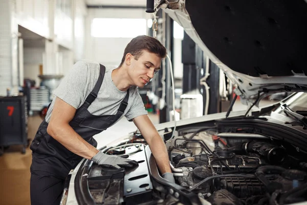 En el trabajo: un mecánico de automóviles está buscando errores en un motor Imágenes De Stock Sin Royalties Gratis