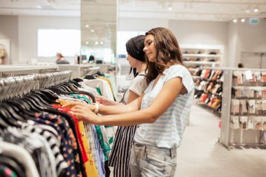 İki iyi görünüyor rahat tarzı, uzun siyah saçlı, ince kızlar gülümseyen var içinde modern bir alışveriş merkezi.