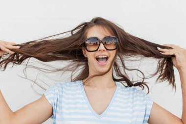 Casual elbiseler giymiş bir genç Şirin ince esmer kız, kameraya bakarak ve saçını tutan .