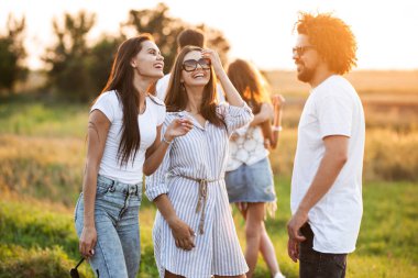 Kıvırcık delikanlı ile sohbet ve sıcak bir günde açık gülüyor iki genç esmer kadın.
