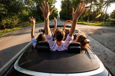 Şirket bir cabriolet yolda sürme ve sıcak güneşli bir günde ellerini dayanabiliyor gençlerin. Arkadan görünüm.