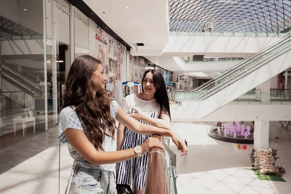 Δύο χαριτωμένο λεπτός μελαχρινός νέος, στέκονται δίπλα στο άλλο σε ένα σύγχρονο εμπορικό κέντρο. — Φωτογραφία Αρχείου