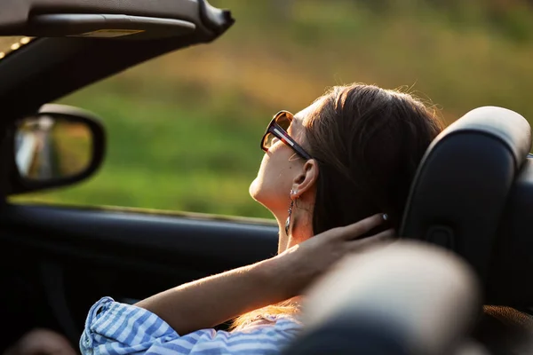 Jeune femme aux cheveux bruns en lunettes de soleil assis en concert le jour ensoleillé . — Photo