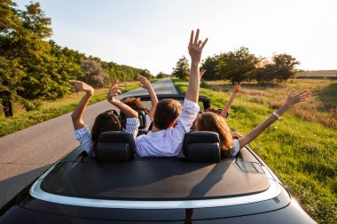 Siyah cabriolet ülke yola çıktı. Genç kızlar ve çocuklar şirket oturan araba ambarda ellerini güneşli bir günde.